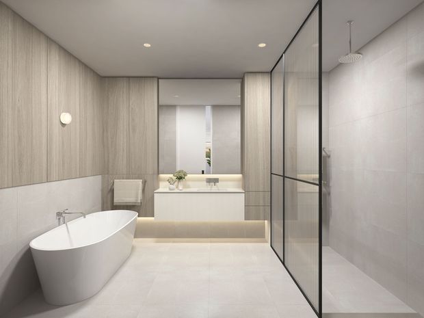 A bright, contemporary bathroom featuring a freestanding white bathtub, floating double vanity with under-cabinet lighting, large pale floor and wall tiles, warm light-wood wall panelling, and a frameless-style glass shower enclosure with black metal framing.