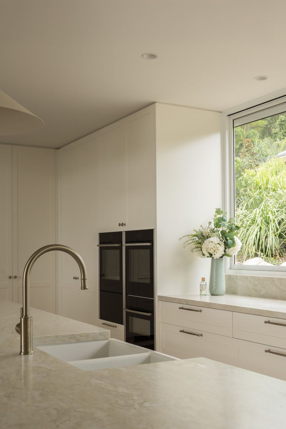 Euroa Farm - Kitchen. Gooseneck tap and integrated ovens with a garden outlook.