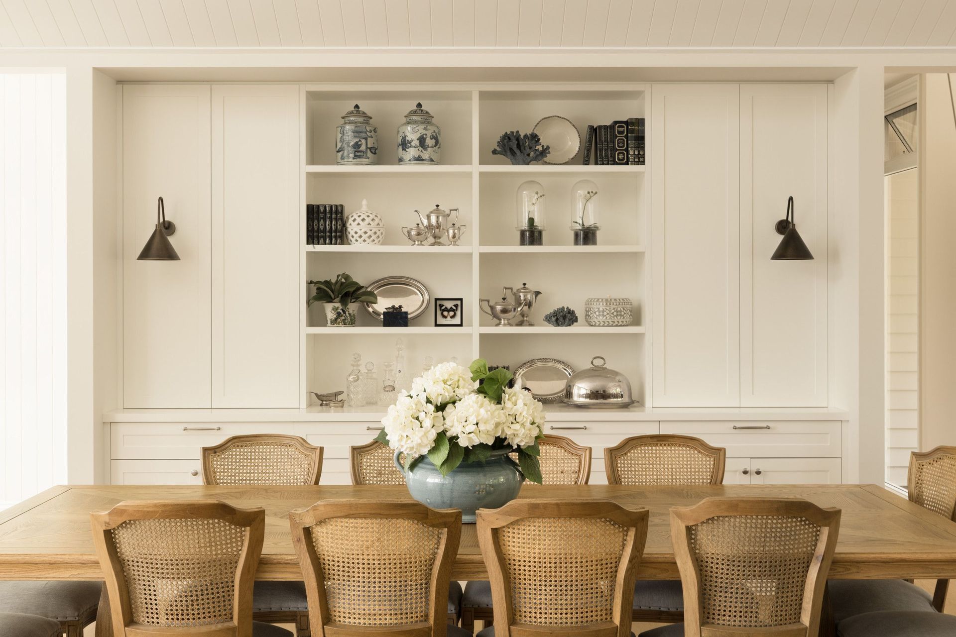 Euroa Farm - Dining Room. Rattan dining chairs before a styled display cabinet.