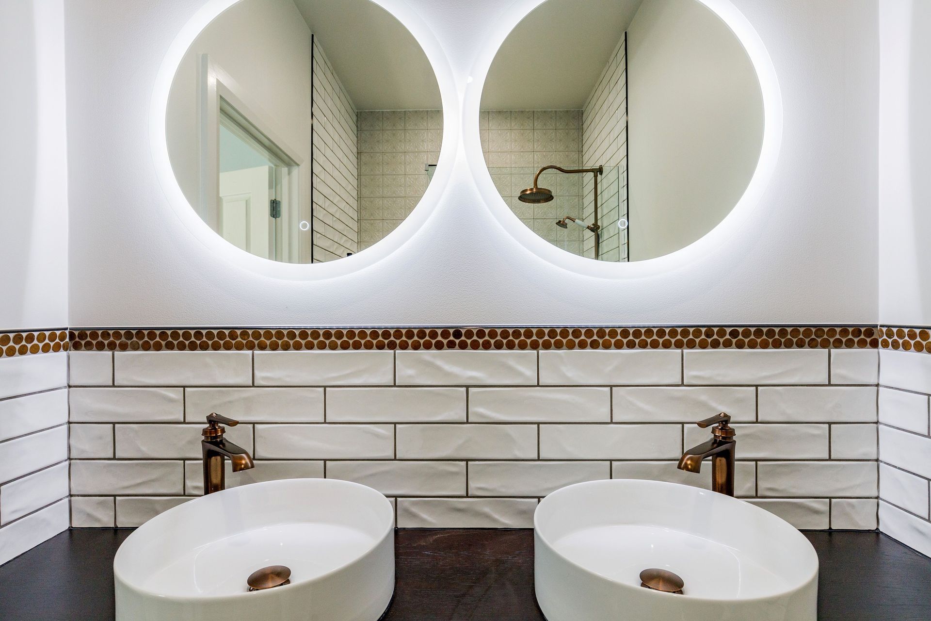 The custom-made timber vanity from newtech's Milazzo Modular Range adds warmth. The Newtech Quarto Round Vessel Basins are accentuated with Waterware - Liberty Range_- Tall Basin Mixer and Clickclak Waste with Overflow, both in Oil Rubbed Bronze Finish.