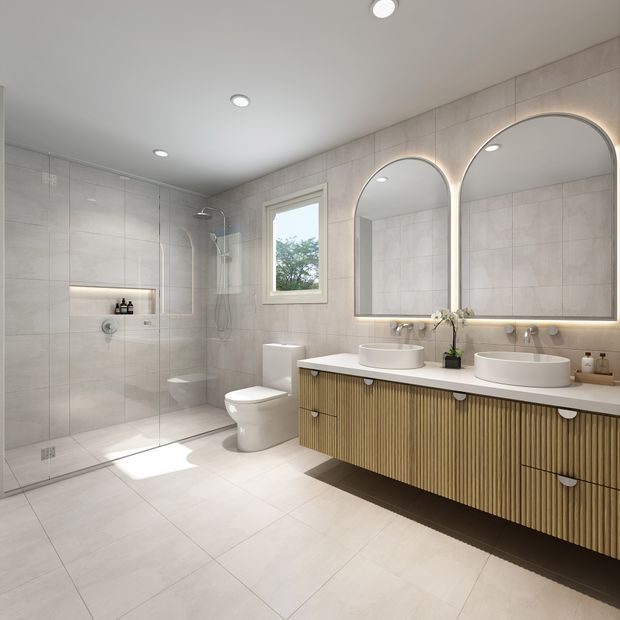 Bright contemporary bathroom with large pale tiled walls and floor, a frameless glass walk-in shower, wall-hung toilet, and a long double vanity with fluted timber cabinetry, white countertop, vessel basins, and arched backlit mirrors. Recessed ceiling lights and a small window provide additional illumination.