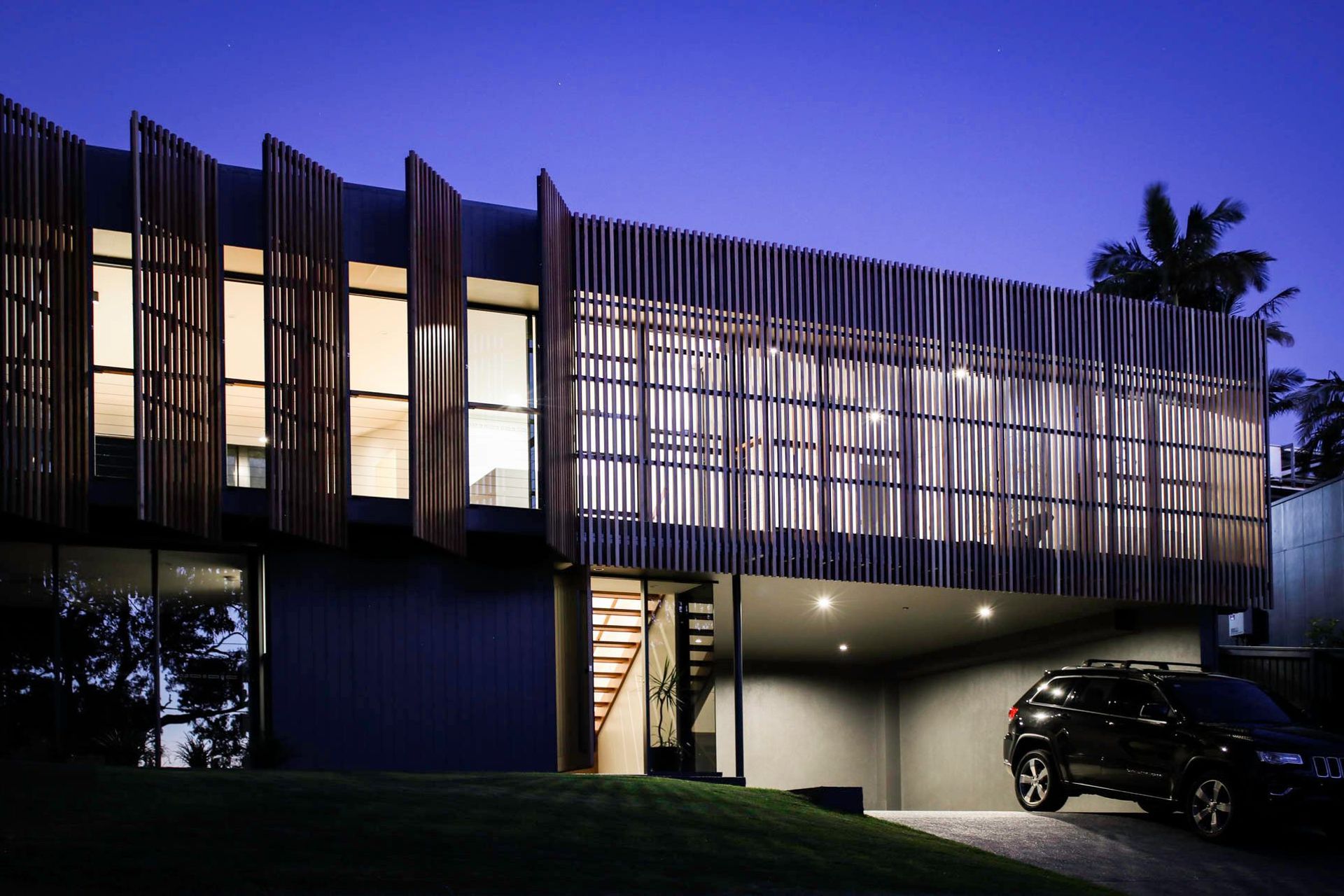 Glennon Residence - Exterior. Street elevation at dusk with glowing timber battened screens.