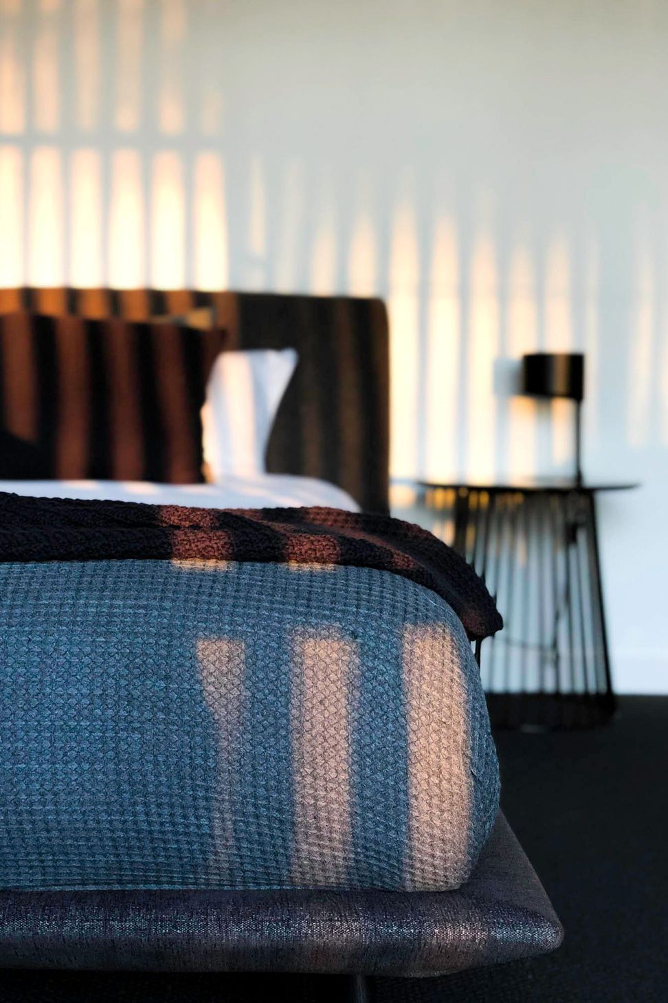 Glennon Residence - Bedroom. Bedroom with a woven throw and timber battens beyond.