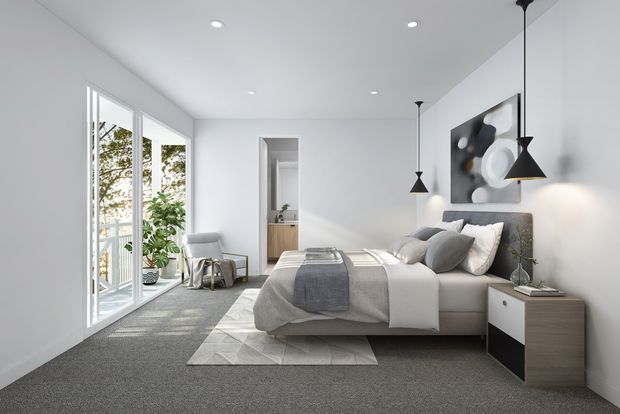 Bright, contemporary bedroom with a neutral palette, low-profile upholstered bed, layered grey and white bedding, simple bedside storage, pendant lights, recessed ceiling lights, abstract wall art, and full-height glazed doors opening to a small outdoor area. The room has soft carpet flooring and a clean, minimalist presentation.
