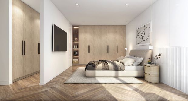 Bright, contemporary bedroom with extensive light timber built-in wardrobes and cabinetry, a low upholstered bed, wall-mounted television, integrated shelving, pale walls, and a herringbone timber floor. Ribbed wall panelling, minimalist pendant lights, and abstract artwork add refined detail.