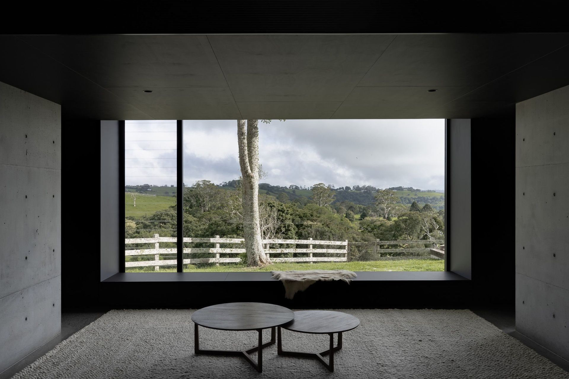 The Farm - Living Room. Dark lounge framing a picture window over the hinterland.