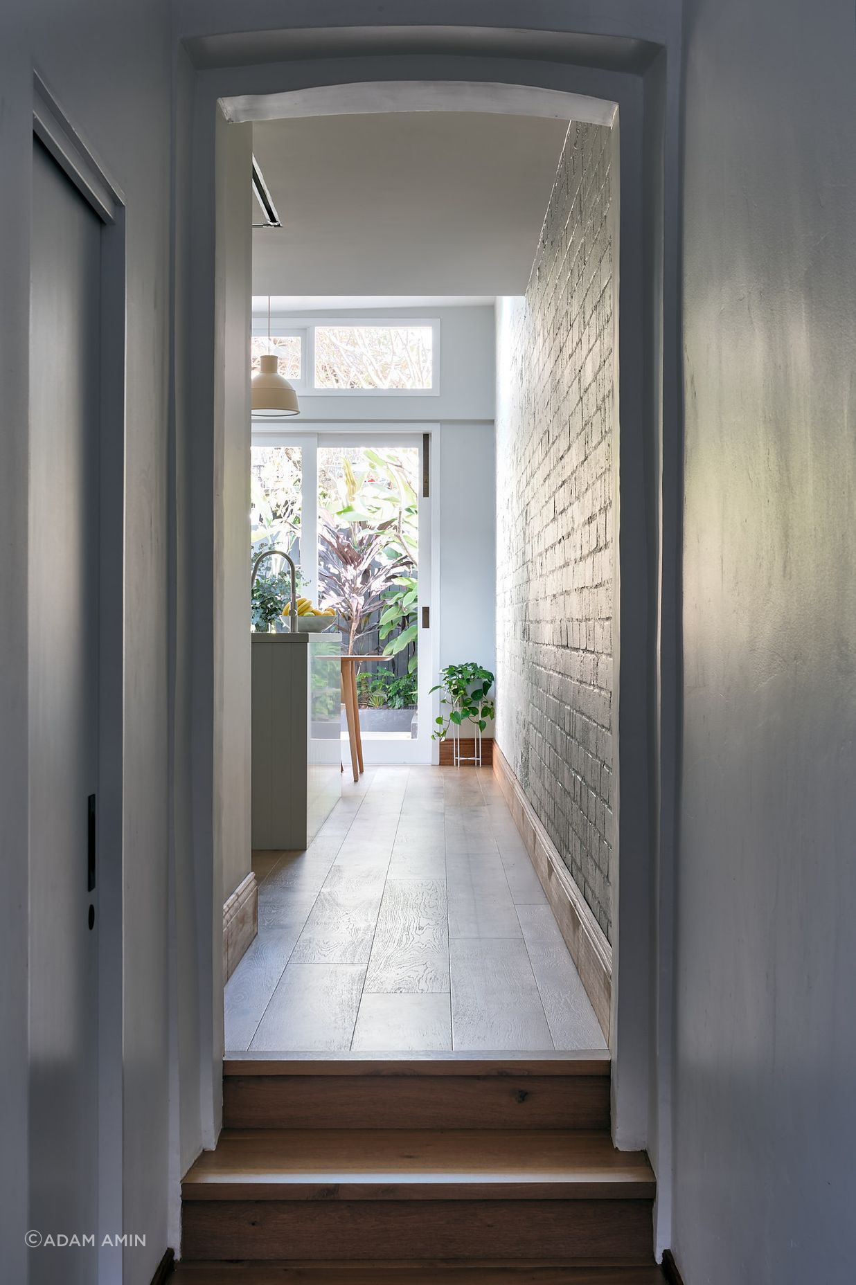 The narrow hallway leading to the home's original termination is a vestibule to the light-saturated open-plan kitchen and adjacent dining spaces.