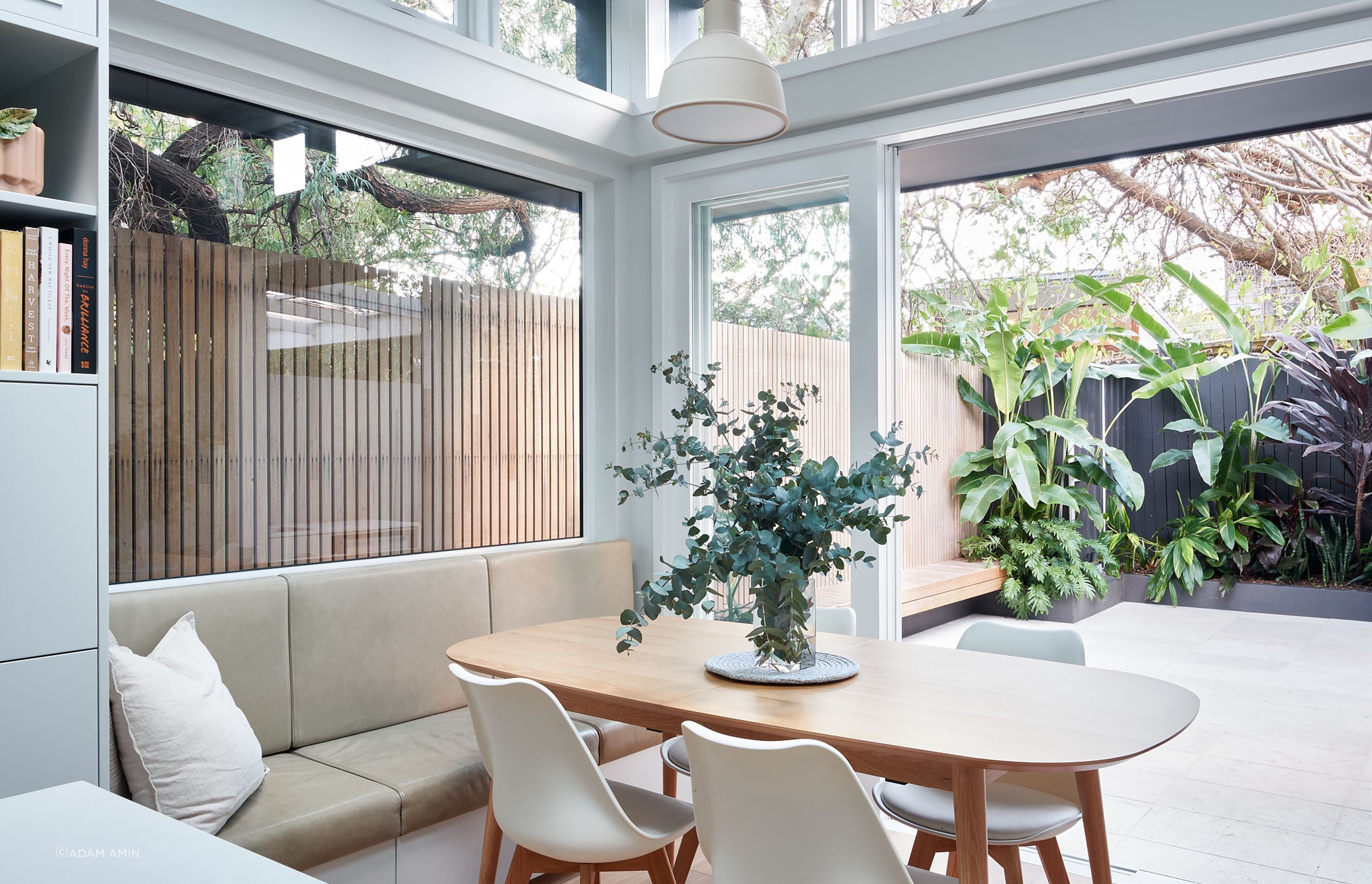 The inbuilt bench braced by the bay window above and sliding doors to the outdoor offer a casual setting for dinner with views of the surrounding vegetation.