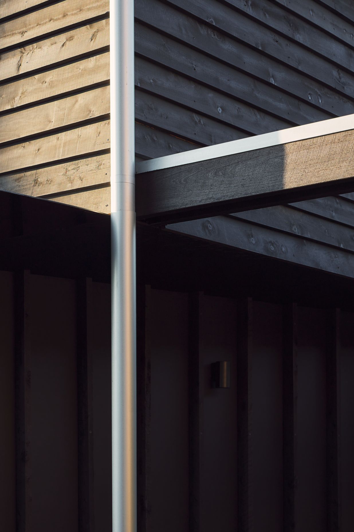 Black stained timber cladding and expressed battens create a muted silhouette for this traditional worker’s cottage, subtly revealing its character and texture throughout the day.⁠