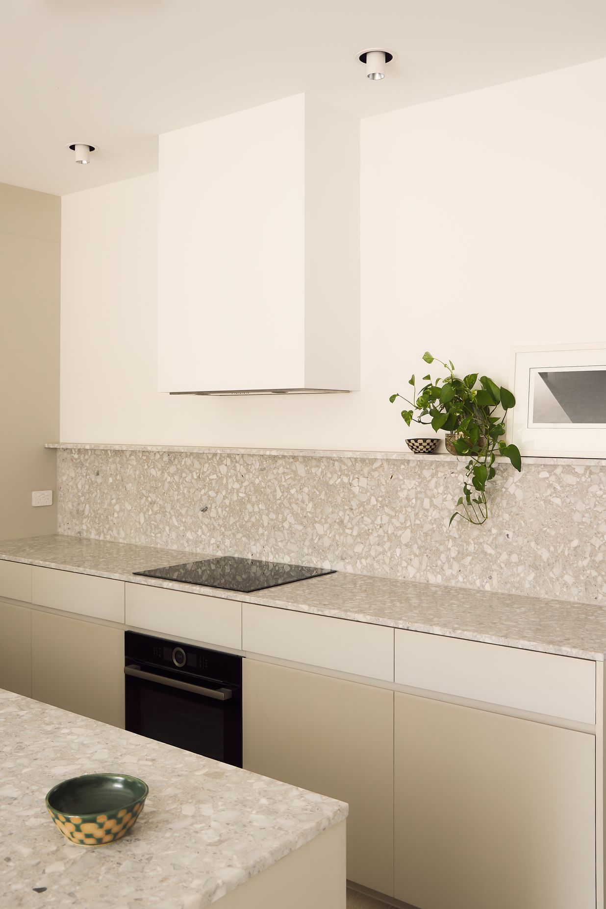 Warm white tones foster a calming ambience in the active lower storey of the house, with textured terrazzo and integrated appliances completing the kitchen and butler’s pantry.