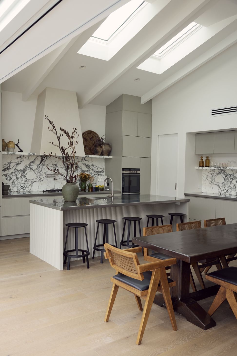 The full sweep of the rear addition at Point Chevalier Bungalow — cathedral ceiling with skylights, Arabescato marble, fluted island and Pierre Jeanneret chairs all coming together in one generous space. In collaboration with Hannah Warren Interiors.