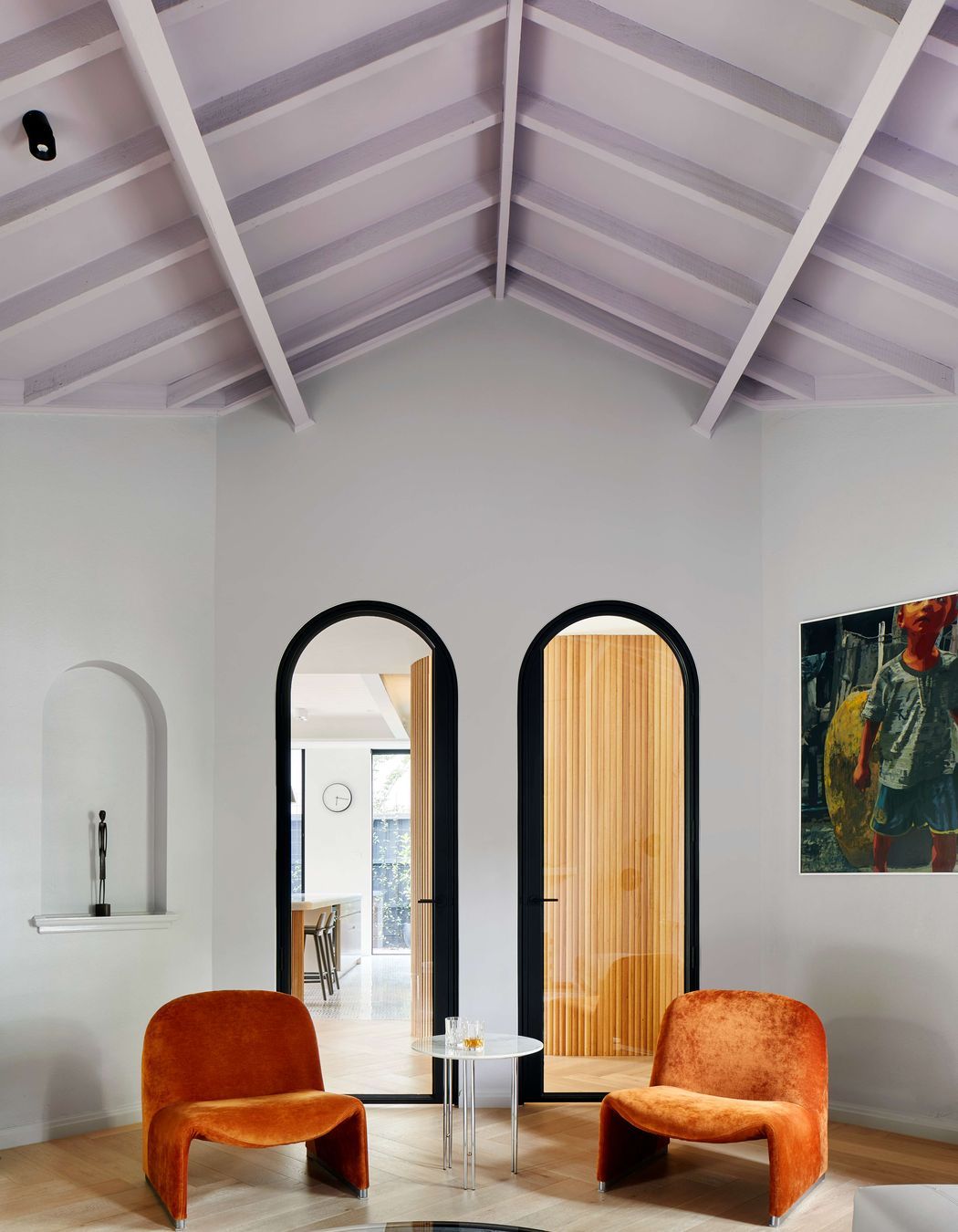 Living room featuring vaulted ceiling painted in mauve from Dulux, with arched doorways, Elke paprika velvet chairs from Castelli and oak flooring laid in herringbone pattern, with a matt lacquer, from our inner easter suburbs project in Melbourne, renovating a 1930’s spanish art deco home. See more from our Arch Deco Project