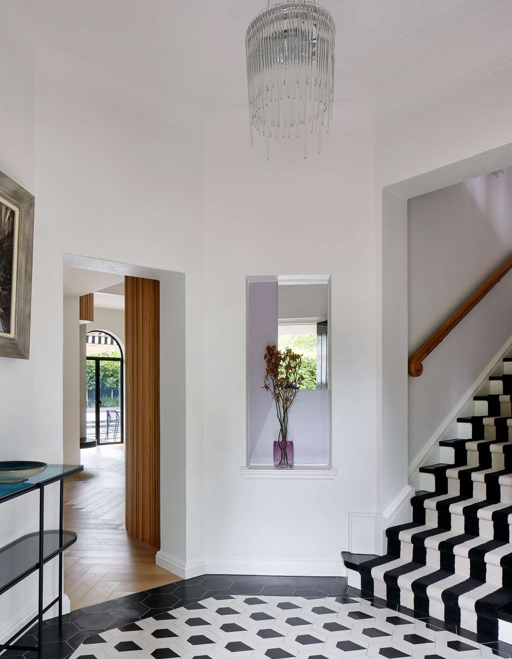 Large black and white art deco entryway with geometric concrete matt tiling from Perini, matched with black and white stairway carpet runner. The project is a 1930s art deco spanish mission style house in Melbourne. See more from our Arch Deco Project.