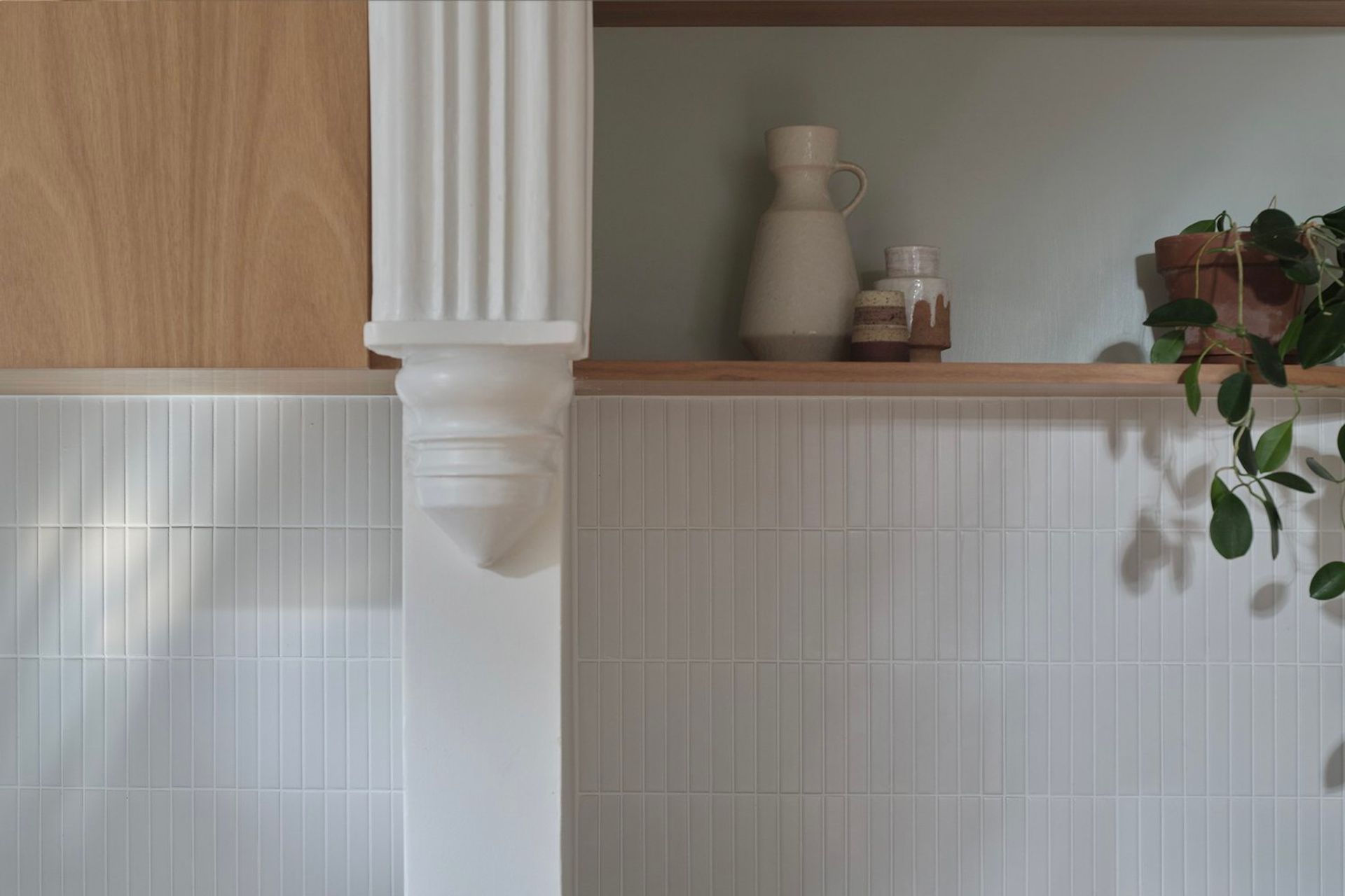 Top cupboards housing the rangehood intersect the kitchen’s dividing wall and continue as open display shelving in the dining room for extra storage and visual balance.