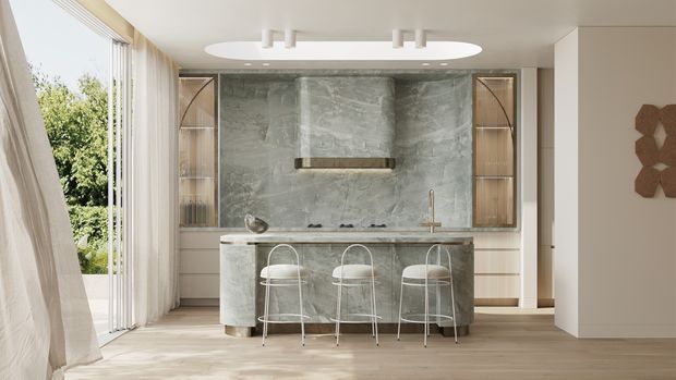Bright contemporary kitchen with a large central island, three bar stools, pale timber flooring, full-height light curtains and glazing, and a dramatic grey stone backsplash extending behind the cooktop. The island includes a dark grey stone benchtop and integrated cabinetry, while warm timber-framed glazed cabinets flank the cooking zone. A sculptural oval ceiling light and neutral finishes create a refined, airy interior.
