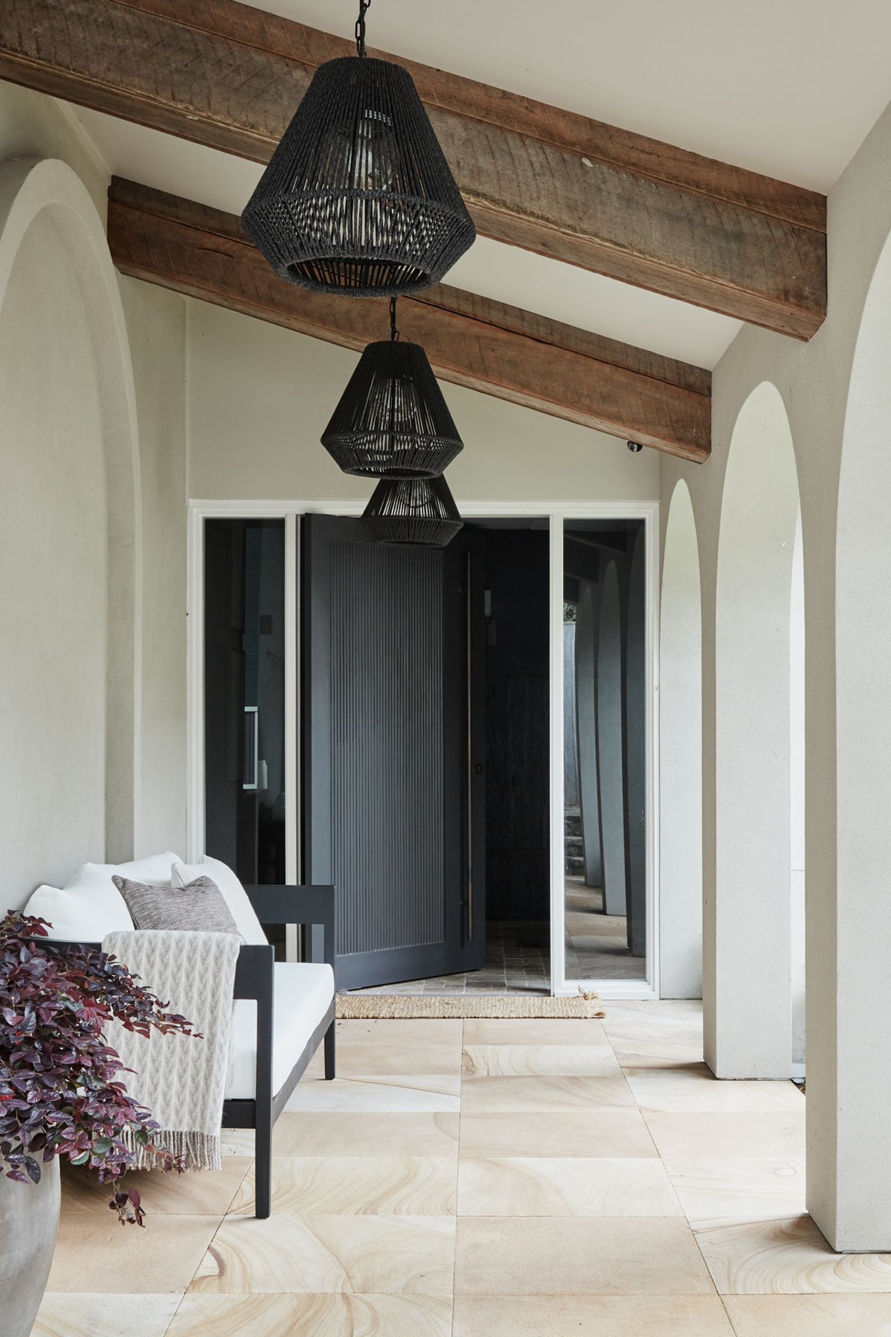 FOYER &amp; ENTRANCE The dark and moody foyer presents a dramatic contrast to the light and breezy covered walkway leading to the front door. Phillip Jeffries ‘Manila Hemp’ wallpaper in Charcoal, The Textile Company. Dark travertine tumbled cobbles, Aeria Country Floors. Arteriors ‘Hogan’ console and Tanner outdoor pendant lights, Boyd Blue. Accessories, Kate Nixon. Avoca outdoor sofa, Horgans. Jilin terracotta pot, Papaya. Sahara entrance mat, Armadillo.