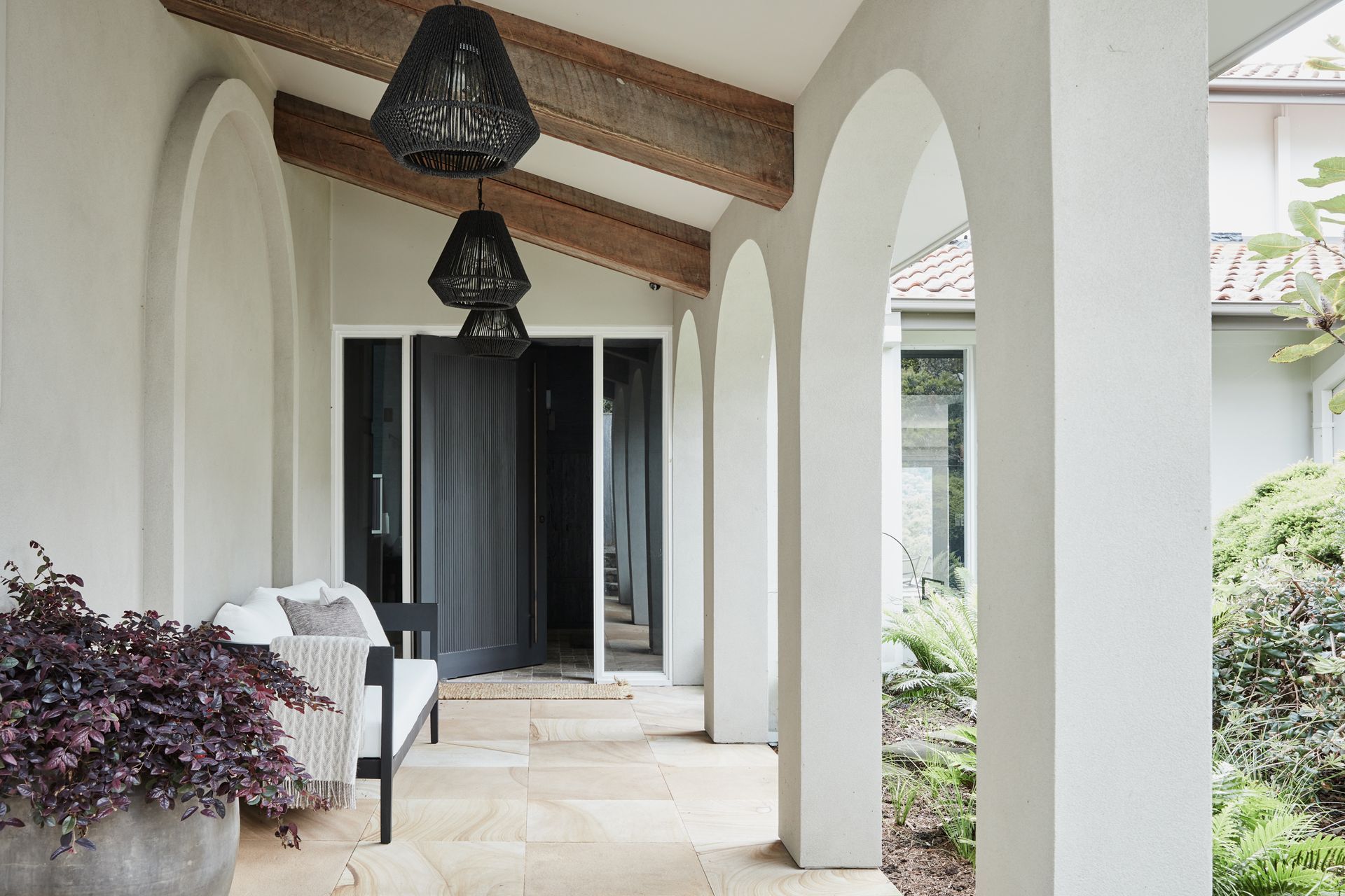 FOYER & ENTRANCE The dark and moody foyer presents a dramatic contrast to the light and breezy covered walkway leading to the front door. Phillip Jeffries ‘Manila Hemp’ wallpaper in Charcoal, The Textile Company. Dark travertine tumbled cobbles, Aeria Country Floors. Arteriors ‘Hogan’ console and Tanner outdoor pendant lights, Boyd Blue. Accessories, Kate Nixon. Avoca outdoor sofa, Horgans. Jilin terracotta pot, Papaya. Sahara entrance mat, Armadillo.