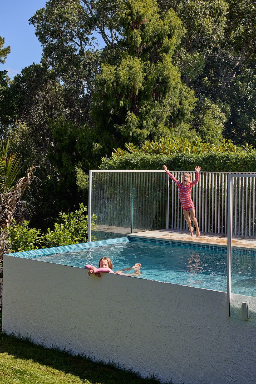 The swimming pool creates the heart of the outdoor living spaces, providing a place for family recreation surrounded by mature trees and landscaped garden.