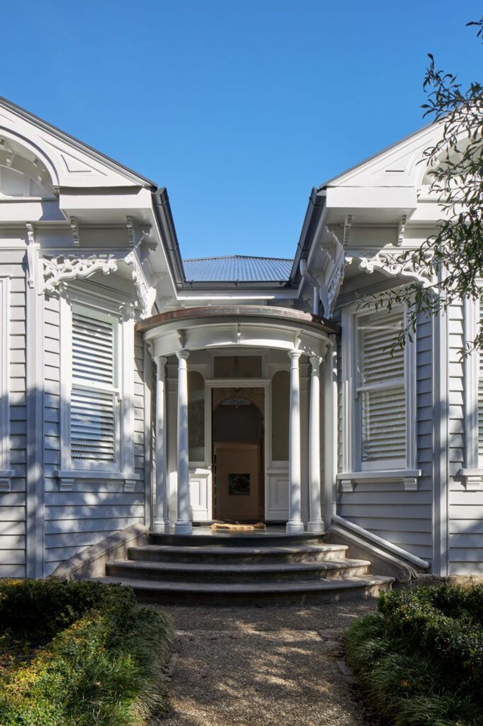 Viewed from the front garden, the restored double-bay villa retains its elegant proportions and original architectural detailing. Mature planting and a welcoming garden path enhance the home's heritage character.