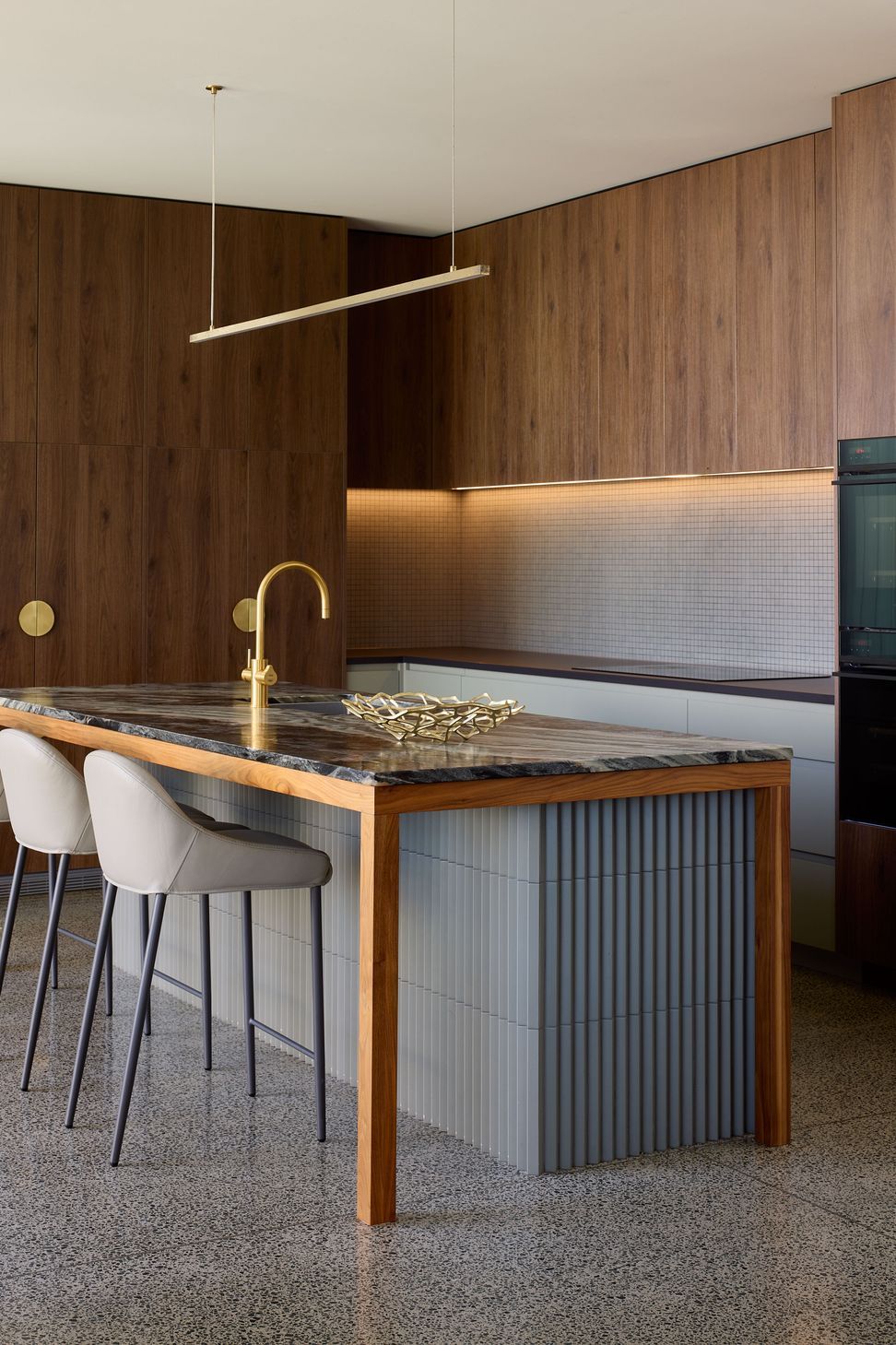 Viewed from the corner of the island, the kitchen showcases its generous layout, bespoke walnut joinery and carefully layered material palette designed for cooking and entertaining.