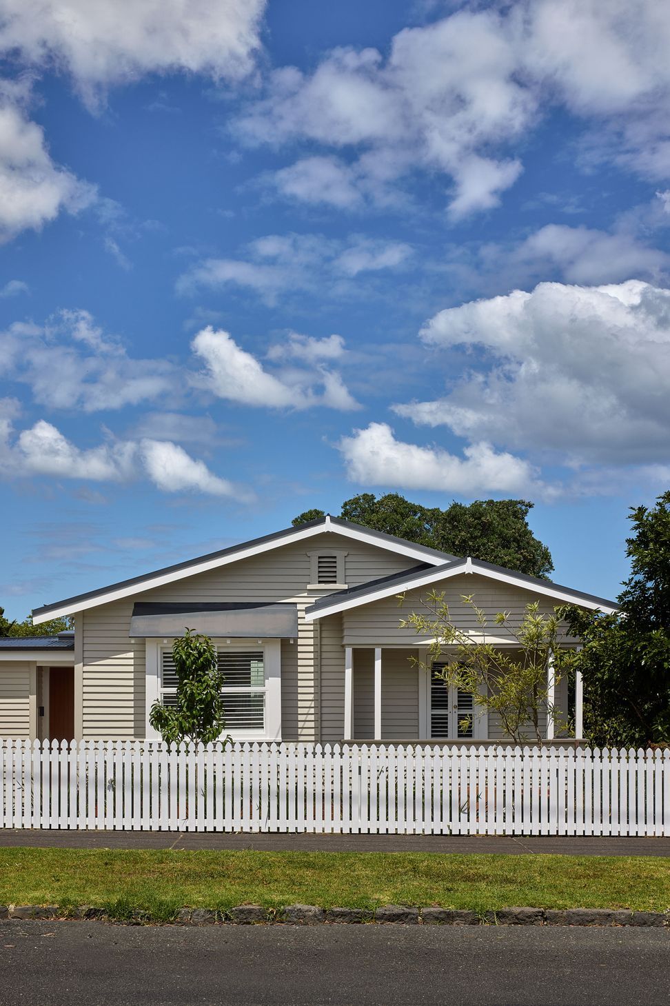 The original bungalow has been carefully restored, with refreshed weatherboards and a traditional white picket fence preserving its welcoming street presence while complementing the contemporary addition beyond.