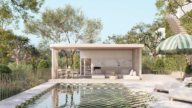 A landscaped outdoor pool terrace with a sheltered, open-sided pool pavilion. The pavilion contains an outdoor kitchen or bar, built-in bench seating, and a dining table, while pale stone paving, a tiled pool edge, lush planting, and a striped awning create a relaxed resort-like setting.