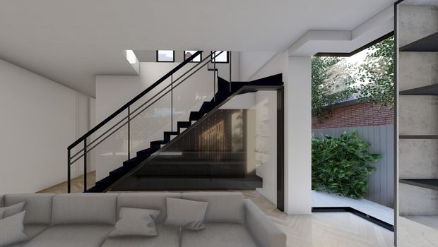 Contemporary interior view centred on a sculptural black staircase with slim metal balustrade and glass panels. A large light-grey sectional sofa occupies the foreground, while a full-height glazed opening on the right looks onto a planted courtyard and brick boundary wall. White walls, pale flooring, dark stair finishes and integrated architectural forms create a refined, high-contrast living space.