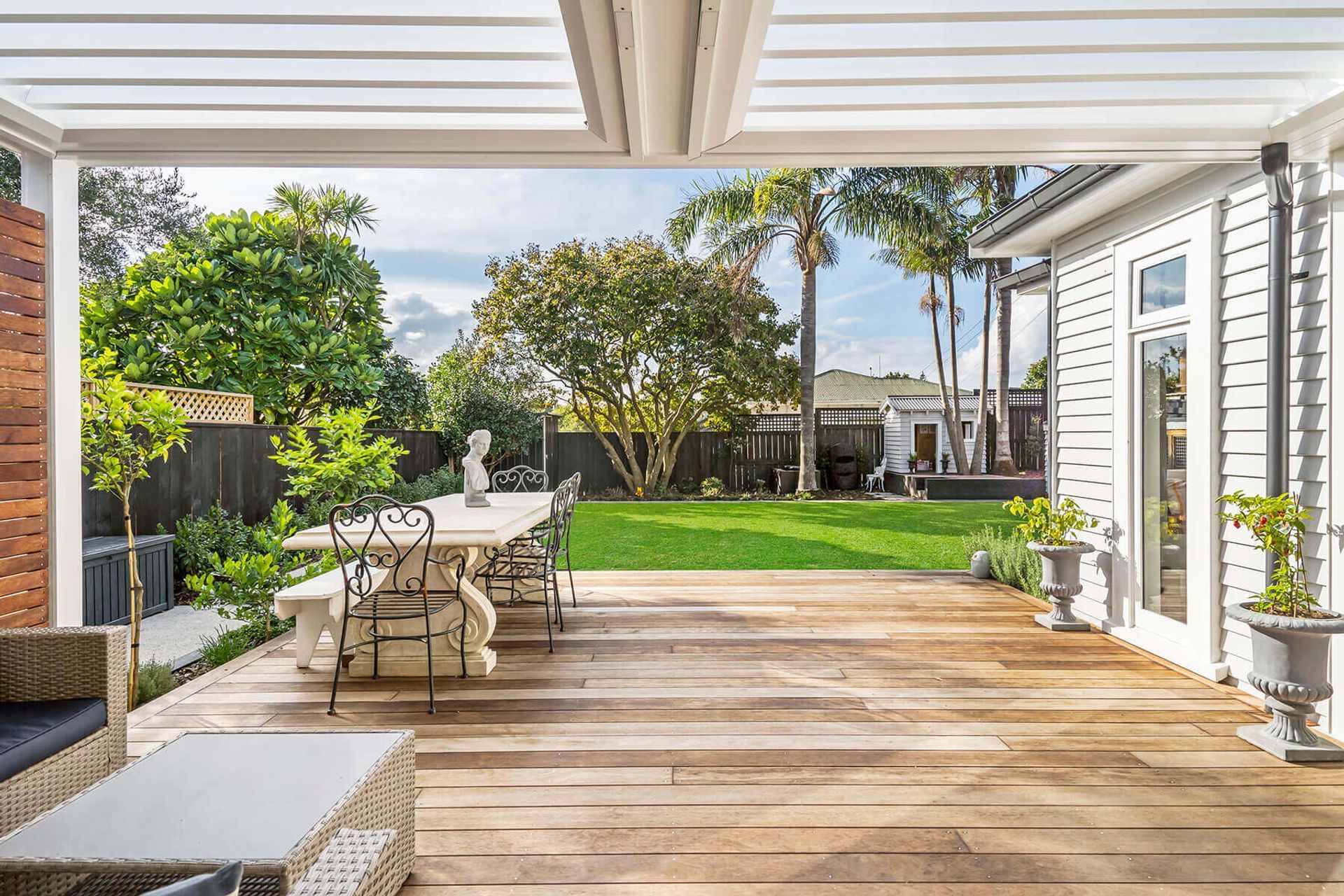 Looking out across the new qwila deck, the garden had new edging laid, as well new planting and mulch. Existing trees were saved and maintained. A new shed provides storage, and the custom playhouse that mimics the style of the house has its own deck that allows the trees to grow through, creating a great children's play area.