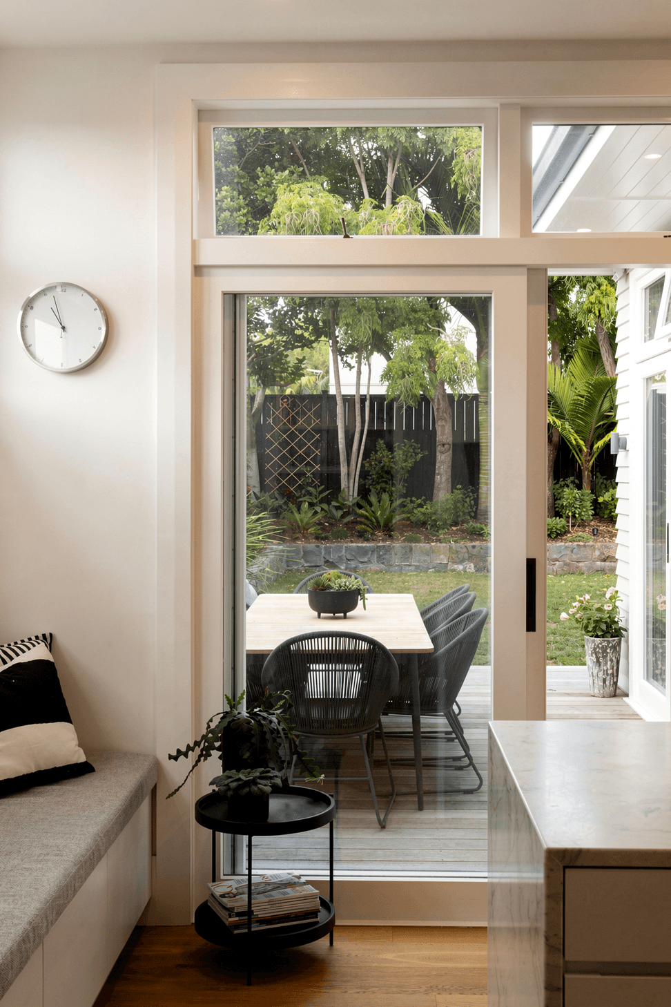 Viewed from the kitchen, the outdoor dining area becomes a natural extension of the living spaces. Timber doors create a seamless connection between inside and out.