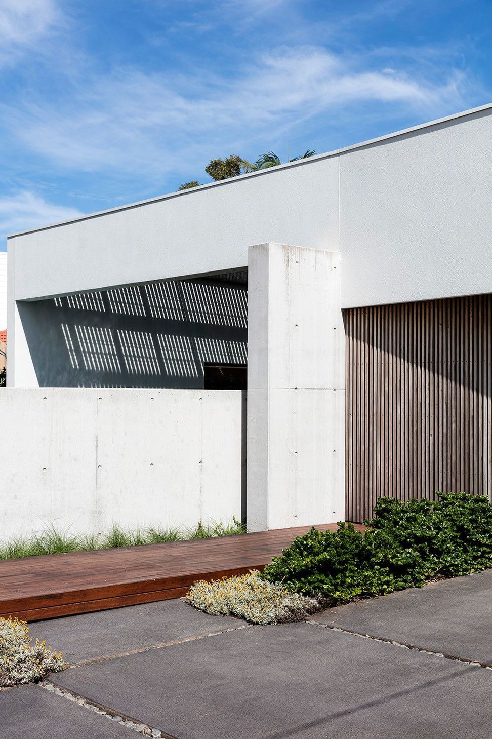 Morrison Residence - Exterior. Concrete fin and timber cladding beneath a floating white upper level.