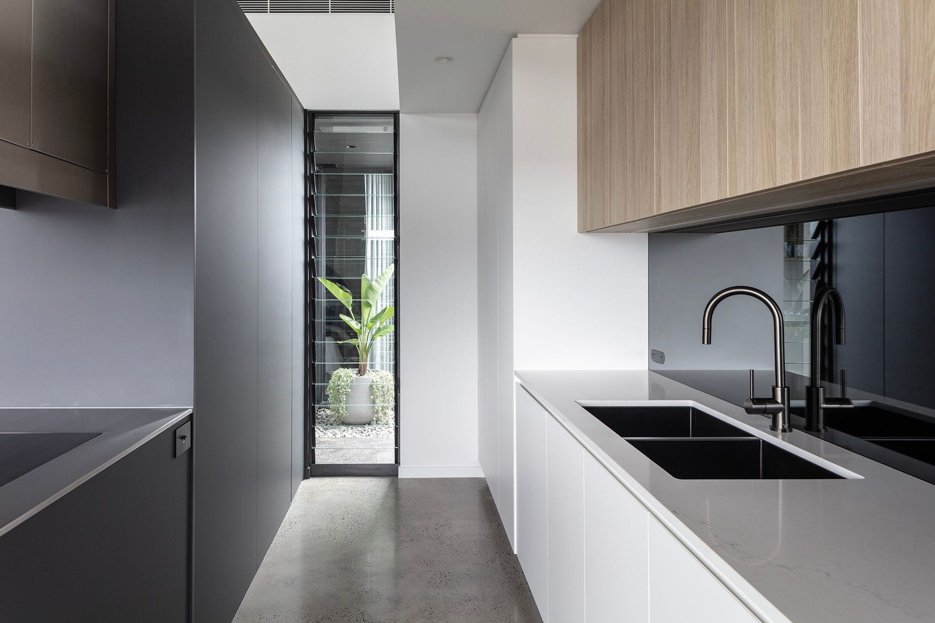 Bells Esplanade - Kitchen. Dark joinery and sink beside a slot window.