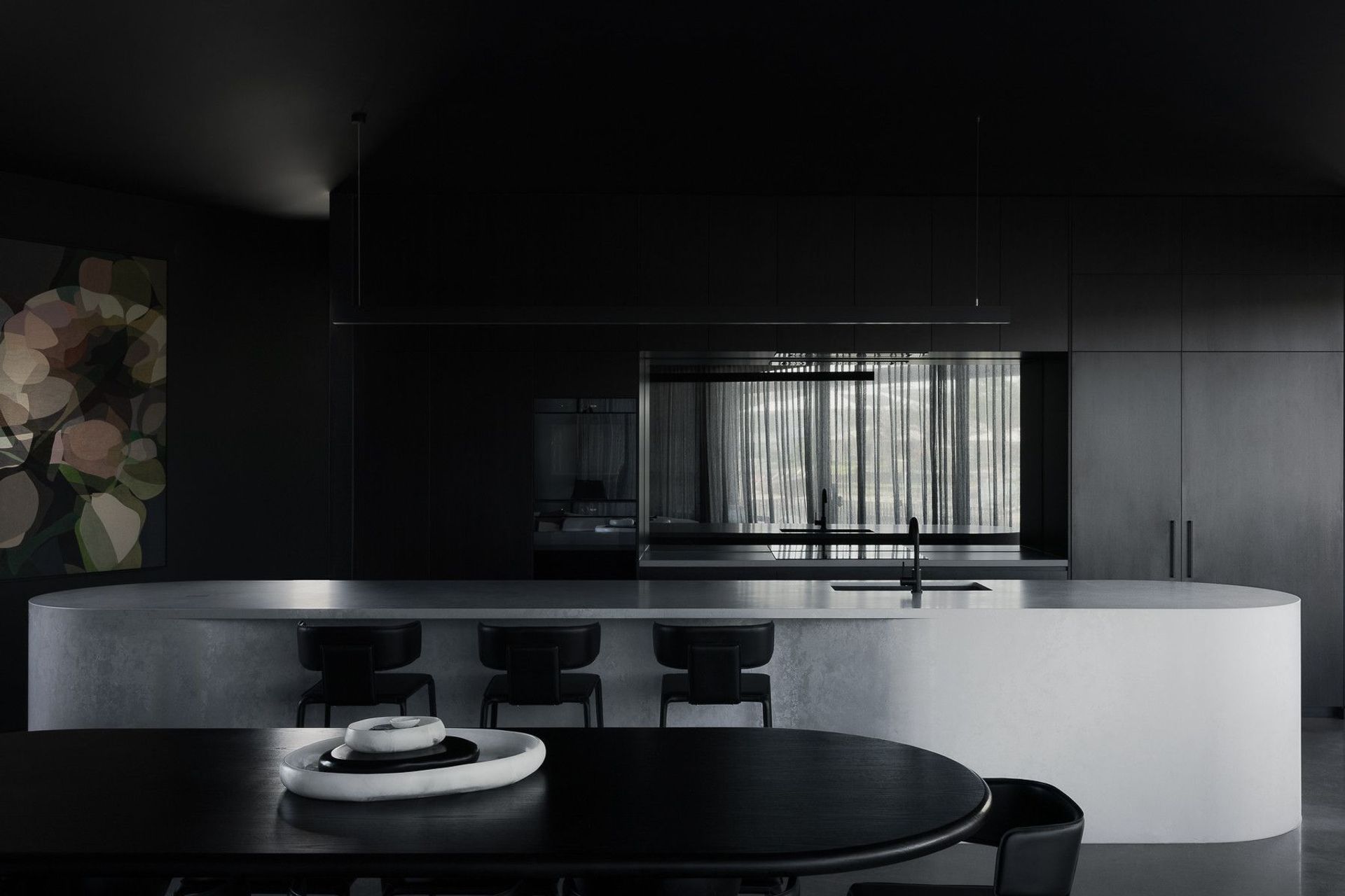 0042 Residence - Kitchen. Moody kitchen with a curved concrete island and black joinery.