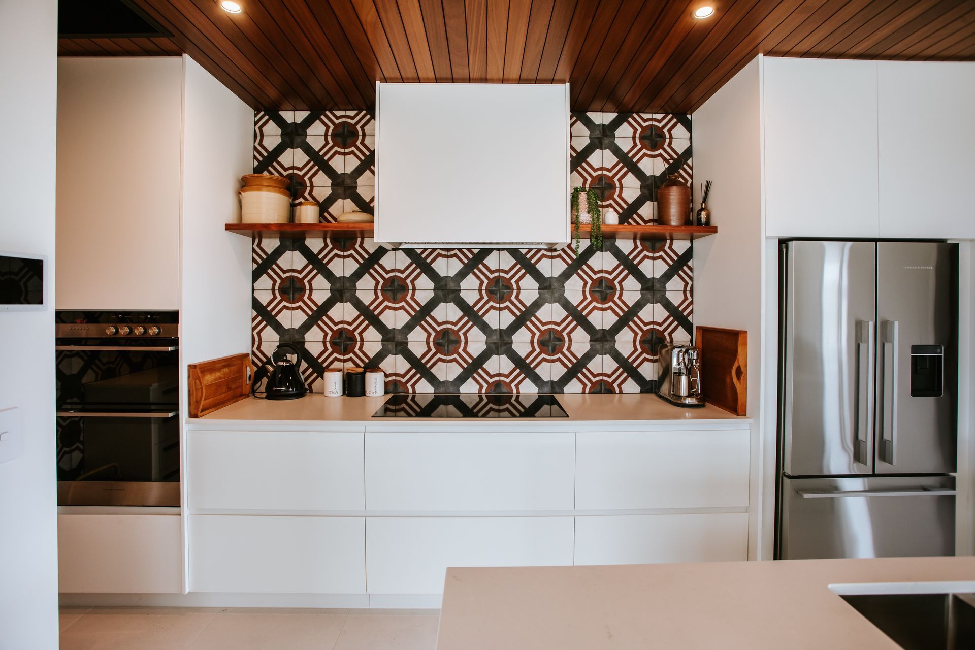 The kitchen features a timber ceiling that delineates the space and combined with the highly patterned tile splashback, the materials create a warm and textured feel.