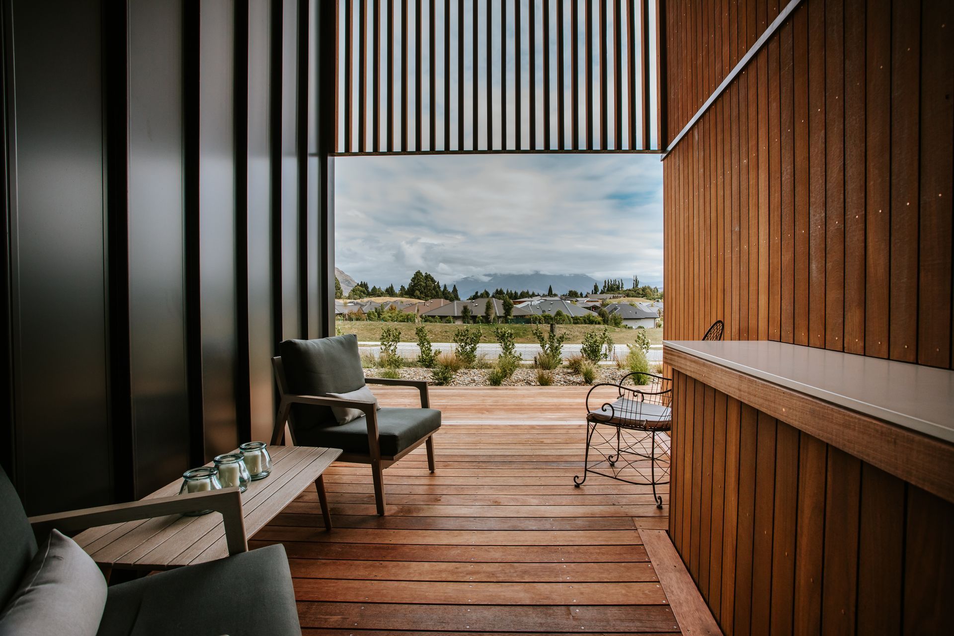 An external sheltered deck space features a built-in bar top in the same material as the kitchen benchtop, creating continuity inside and out.