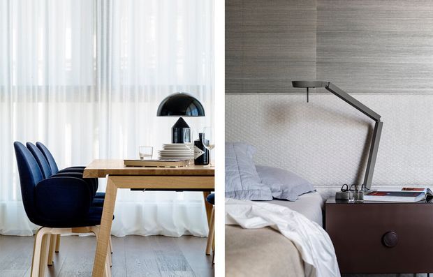 Split interior image showing a refined dining area on the left and a contemporary bedroom on the right. The dining space features a light timber table, deep blue upholstered chairs, sheer white curtains, and a black dome pendant light. The bedroom includes a textured grey feature wall, upholstered bed with pale bedding, dark timber bedside cabinetry, and a sculptural angular desk lamp.