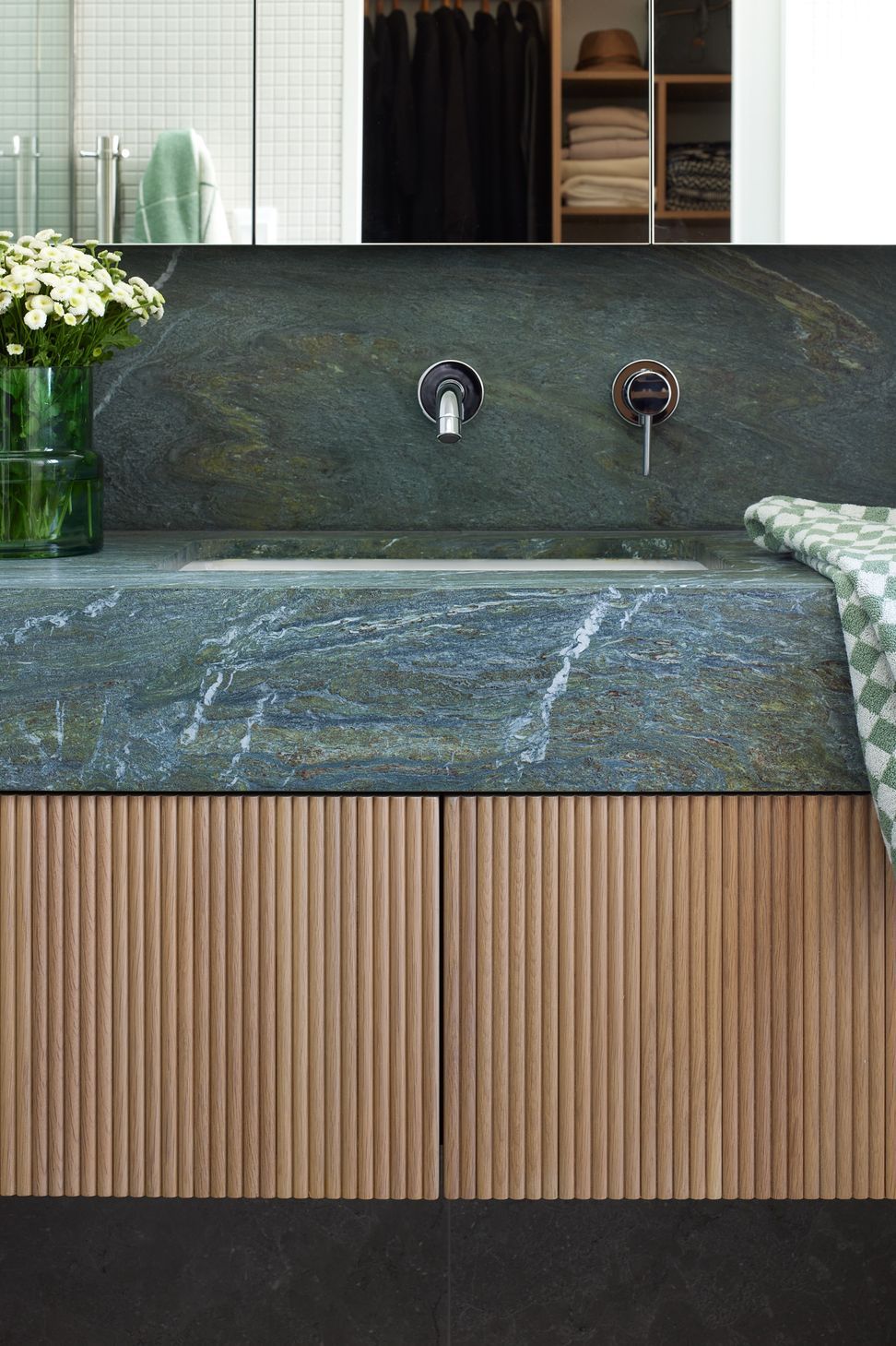 The ensuite combines oak cabinetry with a green stone benchtop and custom mirror cabinet. Carefully crafted details and natural materials create a warm and elegant bathroom.