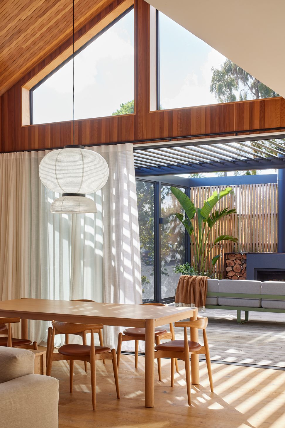 From the dining room, large sliding doors open to the outdoor lounge with its pergola and outdoor fireplace. The cedar-lined skillion ceiling and feature pendant reinforce the connection between indoor and outdoor living.