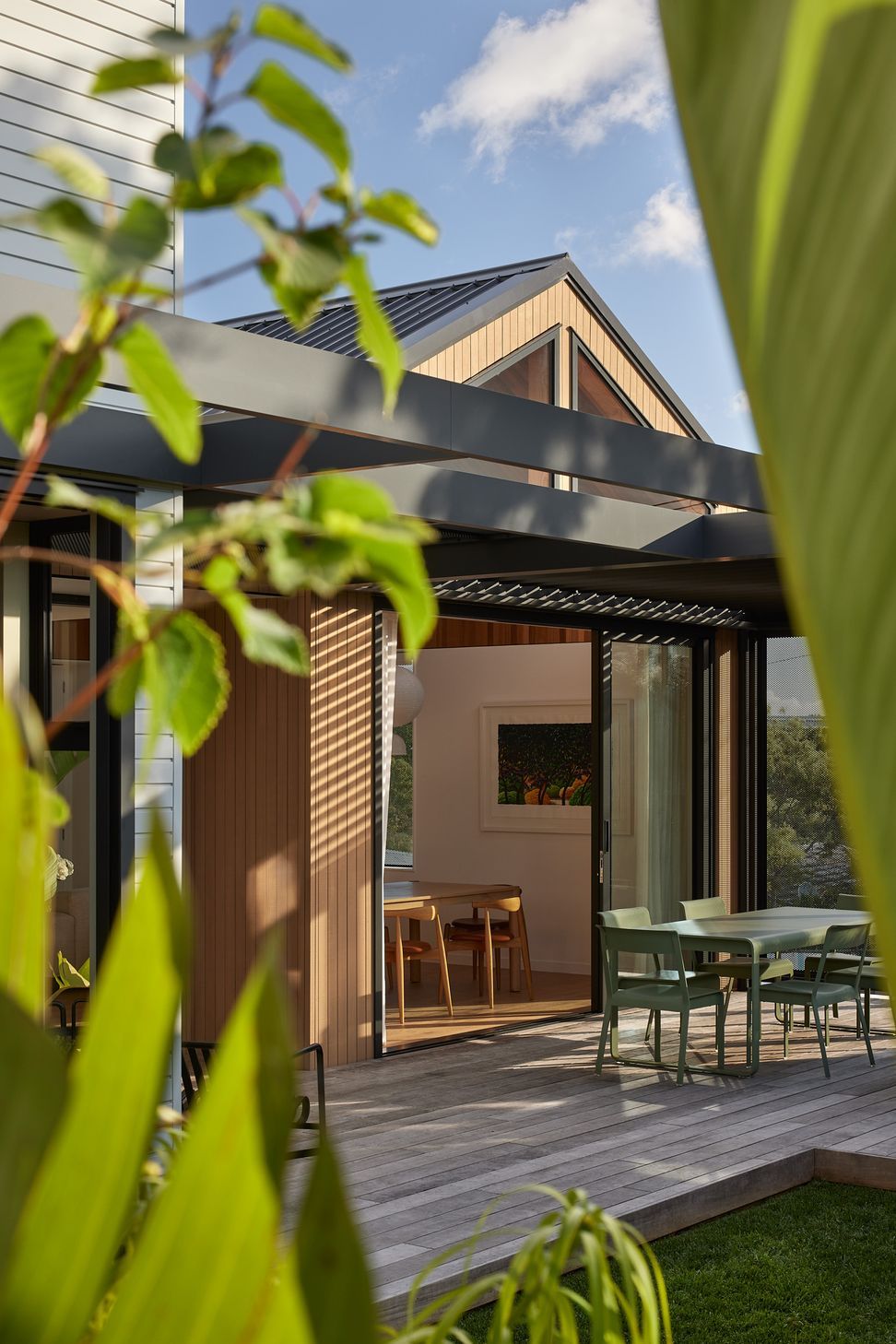 Viewed from the garden, the outdoor lounge flows seamlessly from the dining room. Cedar cladding and a gabled roof give the contemporary addition a warm and timeless character.