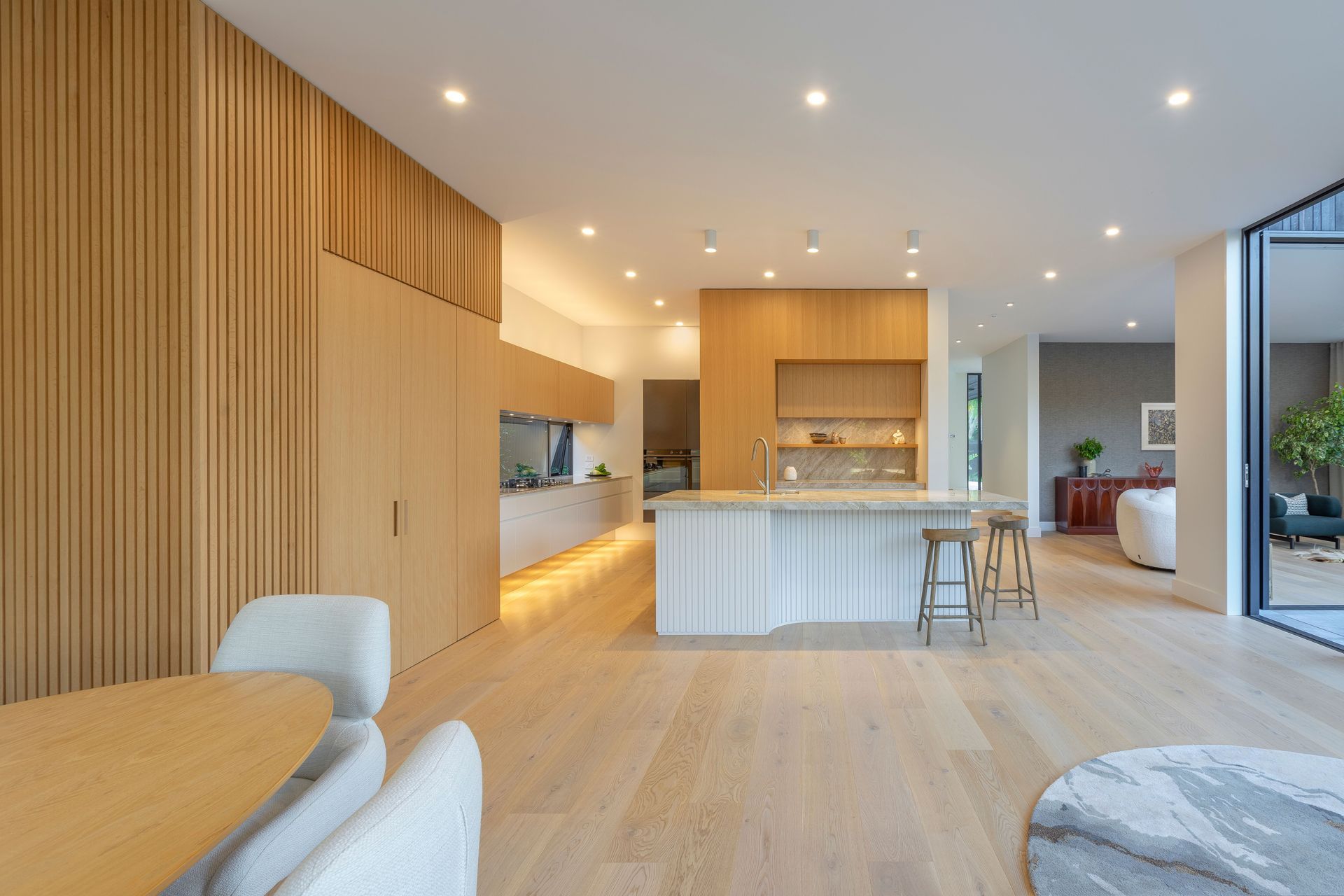 The island continues the battened pleat-like story balanced in white, allowing the stone to shine. For mere delight, Toni carved out a delicate curve to shape a seated gathering place. Each exquisitely crafted batten remains equally spaced using radial modulation geometries, 3D-modelling technology and 1970’s pattern-making techniques.