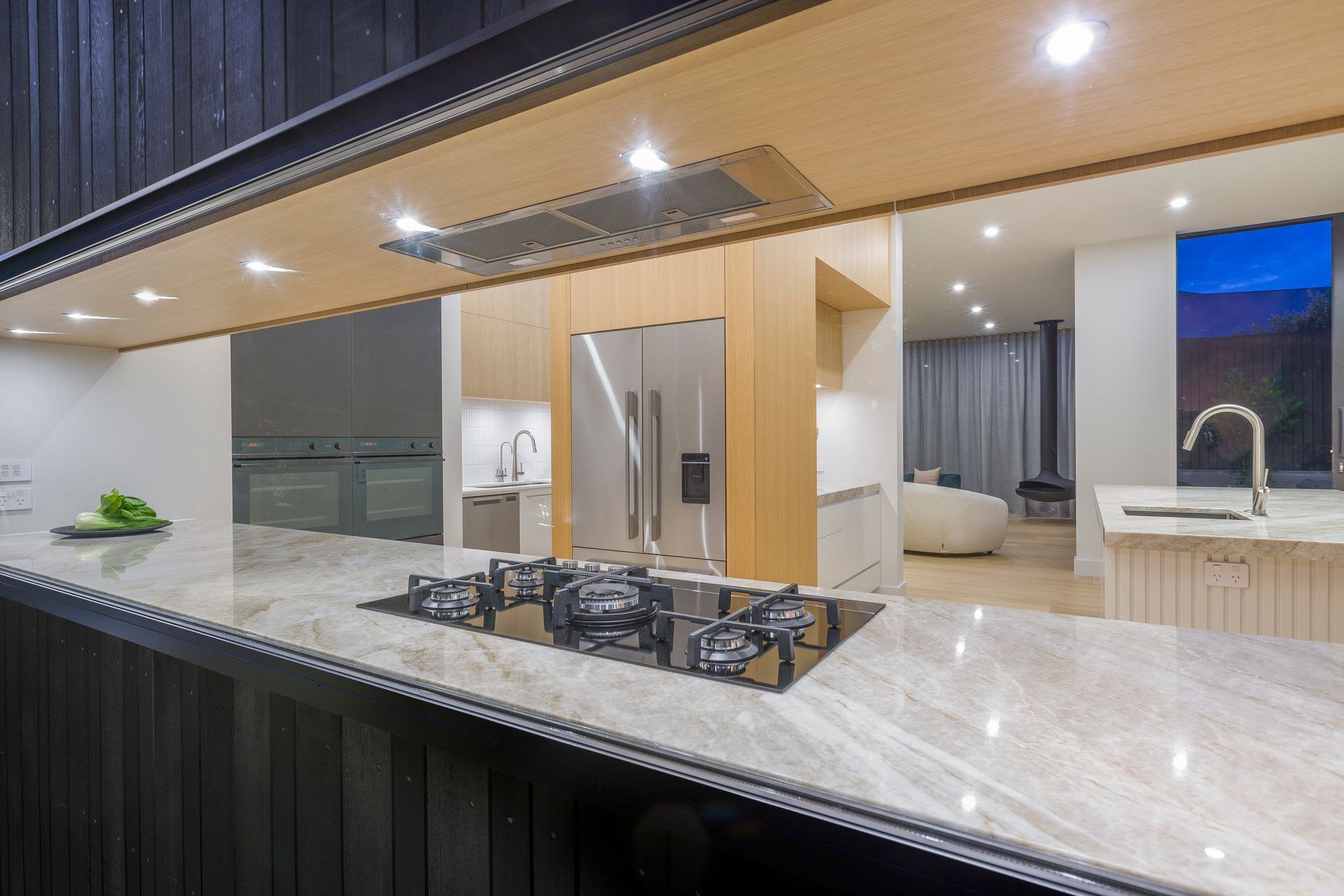 This view from outside reveals the scullery beyond and the attention to fine detailing of each material to the glass frame; a careful collaboration of several trades at site.  Wanting appliances hidden yet intuitively accessible, the fridge and ovens are tucked around the corner for guests' first-impression of elegance.