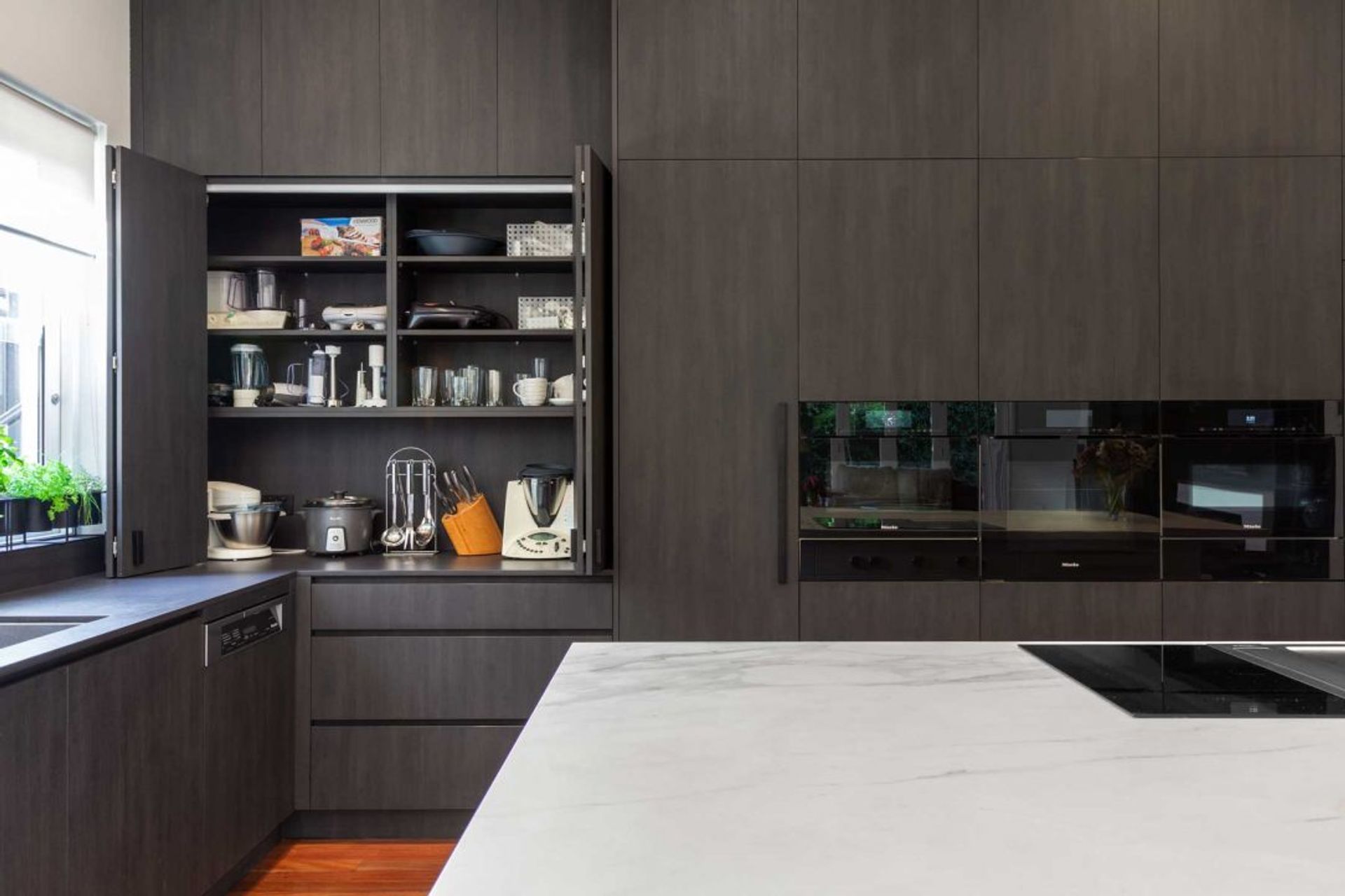premier-kitchen-design-sydney-neolith-dekton-benchtop-splashback-dark-timber-white-appliance-cupboard-1084x723.jpg