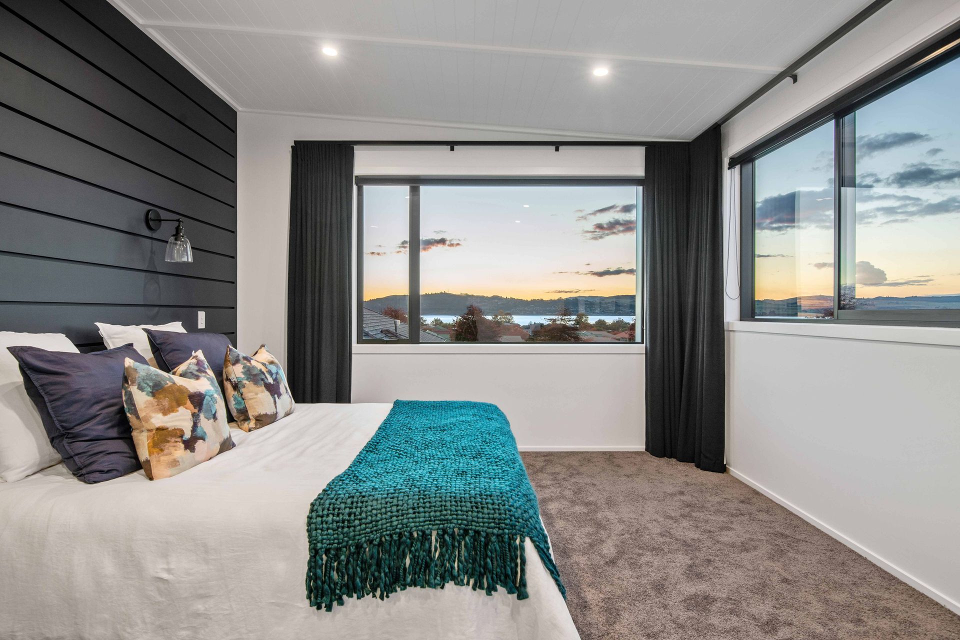 Upstairs, the main bedroom enjoys double-aspect views of the lake and continues the bold black and white theme with accent colours.