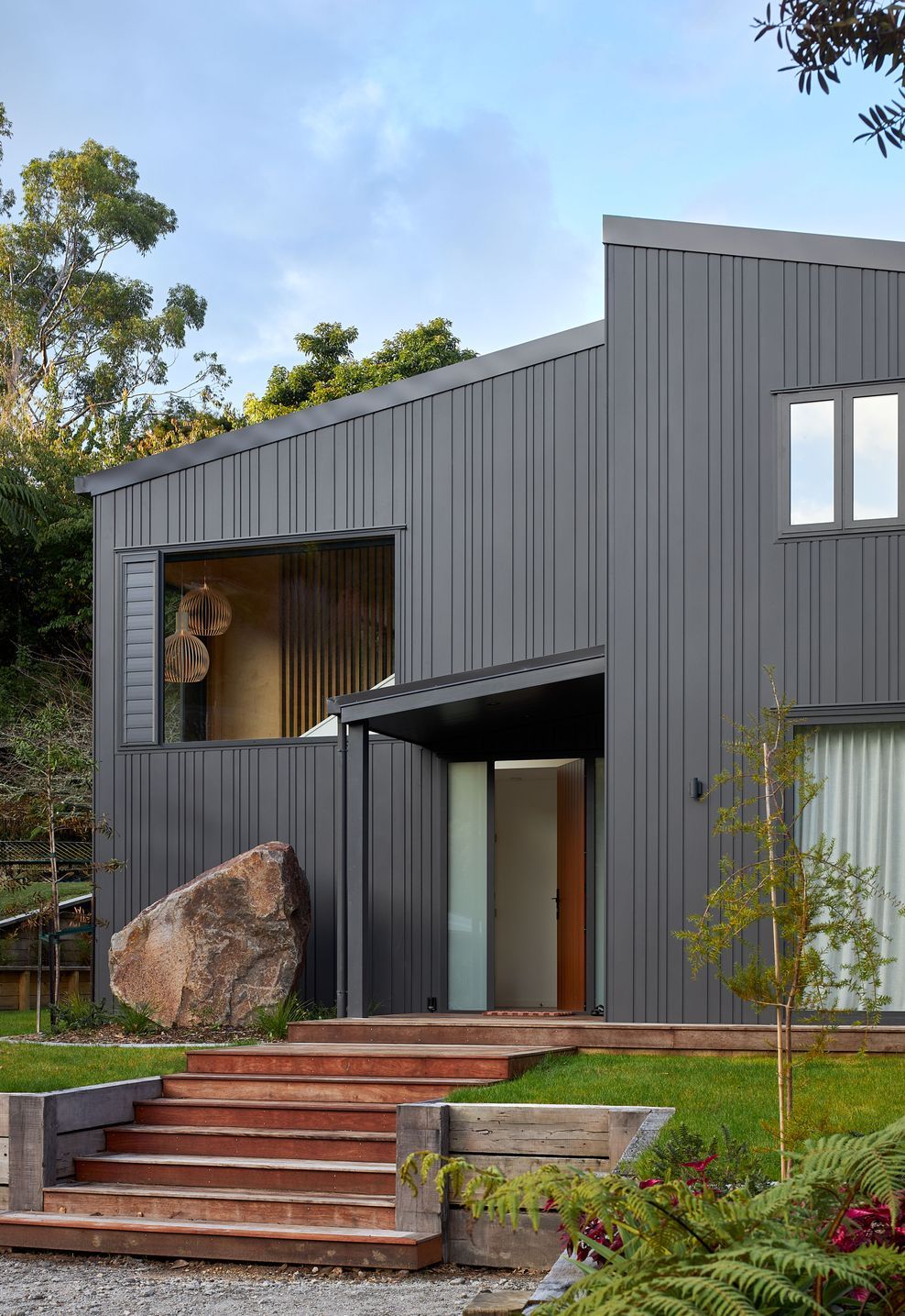 Viewed across the expansive arrival court, The Owl's Retreat presents a calm and understated architectural form. The generously sized forecourt accommodates family gatherings with ease, providing parking for residents and up to five guest vehicles while creating an unhurried arrival experience. Clad in slate grey Nu-Wall, the home's simple gabled forms sit comfortably within the landscape, balancing practicality with a refined architectural presence