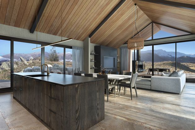 Open-plan kitchen, dining, and living area with a large dark timber island, exposed timber-lined vaulted ceiling, black structural beams, expansive floor-to-ceiling glazing, and mountain views. The space includes a dining table, built-in living area, pendant lighting, and contemporary furnishings.
