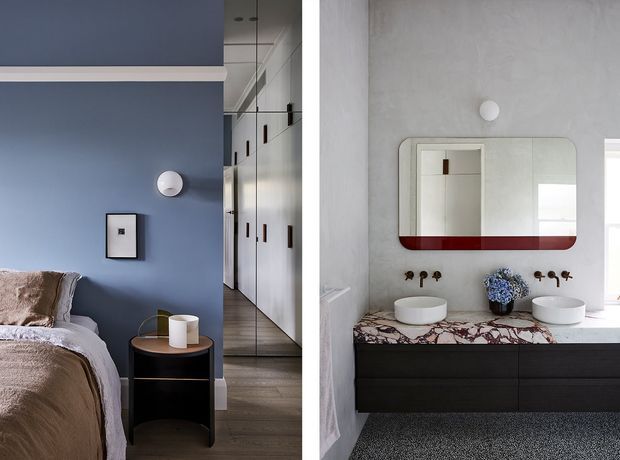 Split view of a refined contemporary bedroom and bathroom. The bedroom has a muted blue feature wall, upholstered bed, dark rounded bedside table, framed artwork, and mirrored wardrobe doors. The bathroom features a floating dark vanity, white vessel basins, a pink-and-white veined stone benchtop, a rounded rectangular mirror with a bold burgundy lower band, and brushed metal wall-mounted fittings.