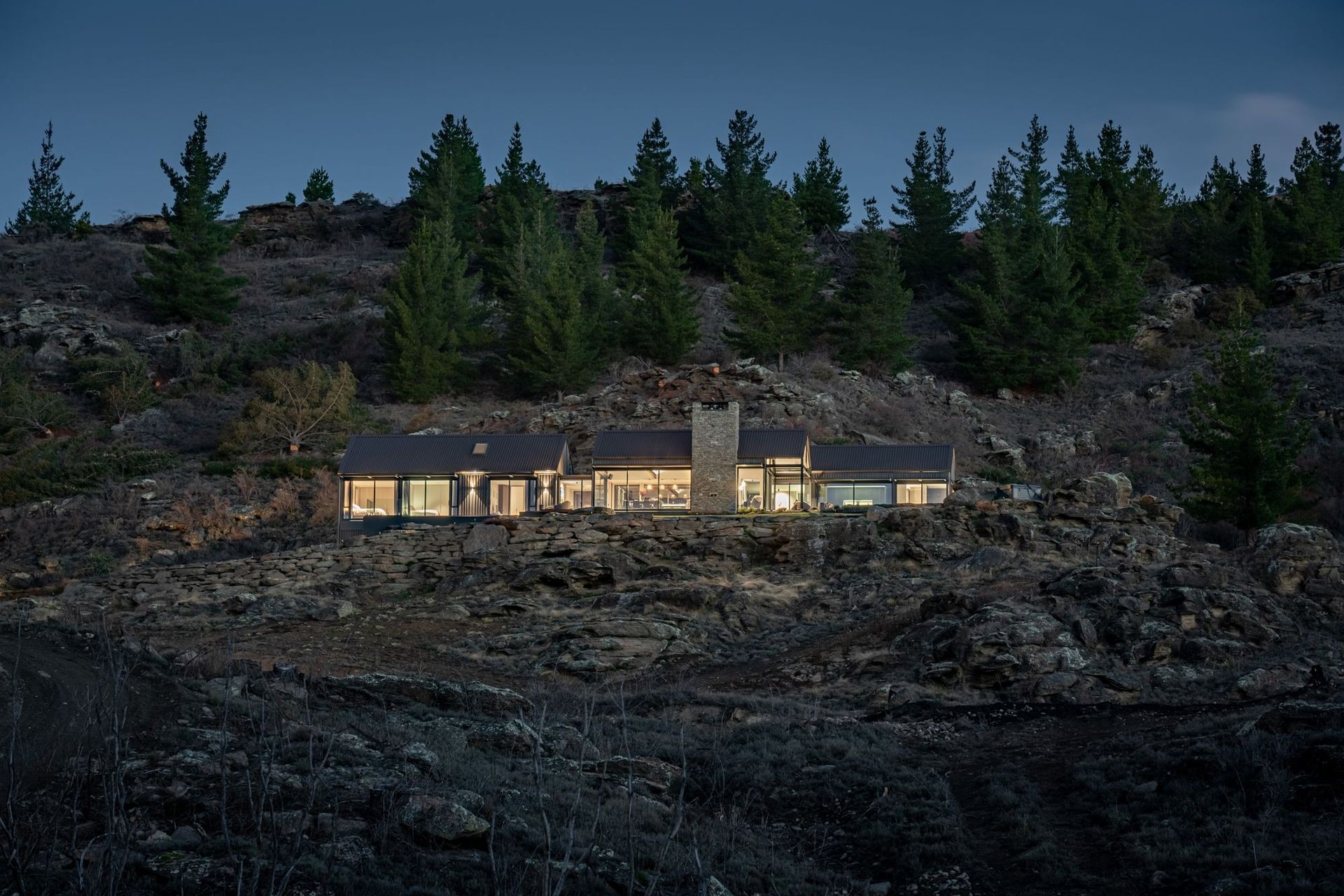 The journey to the home takes the visitor through a winding driveway of schist and poplar trees up to the left of the house, which contains a garage tucked under the bedroom wing.