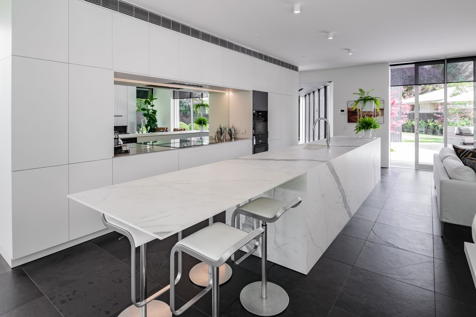 Open and airy, the kitchen features a mirrored splashback.