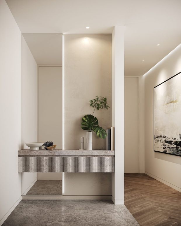 Refined minimalist residential hallway and entry console. A floating fluted-front timber or painted joinery console with a stone-look benchtop sits against a textured neutral feature wall, framed by recessed LED strip lighting and a full-height mirror. Grey stone-look floor tiles define the entry zone, while warm herringbone timber flooring continues through the adjoining corridor. Neutral cabinetry and walls, recessed downlights, restrained decor, indoor greenery, and framed abstract artwork create a calm, contemporary interior.
