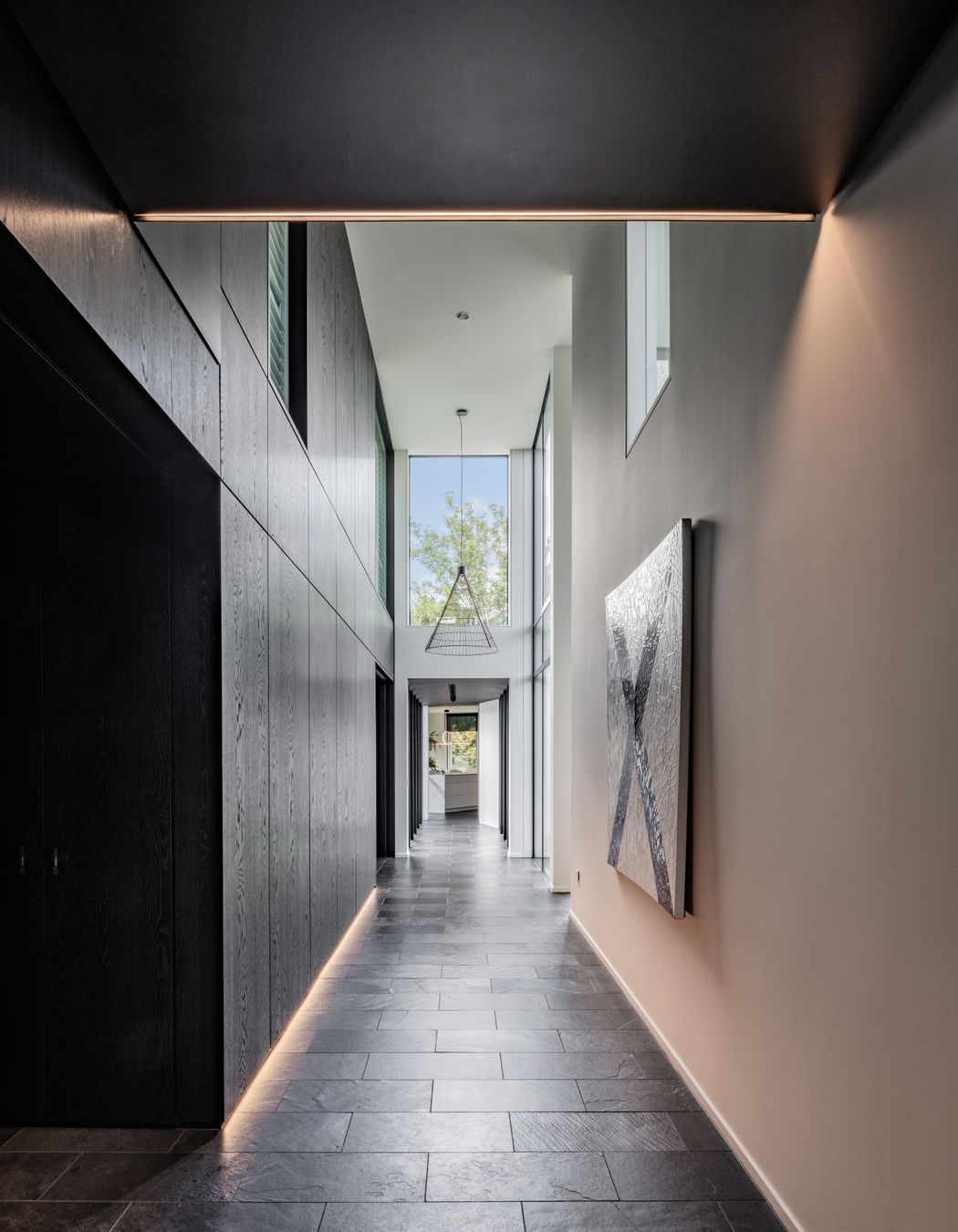 A spine of dark cabinetry conceals the home's private spaces.