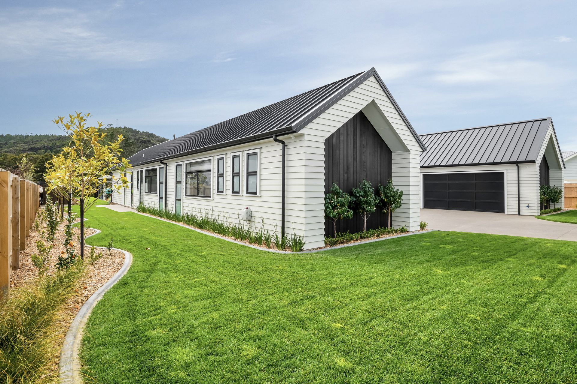 The H-shaped structure offers optimal privacy, with the windows of both wings and the paneled garage doors, crafted by Jones Doors, all perpendicular to the street.